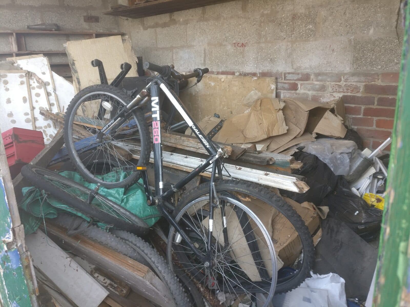 Bicycles, boards and boxes piled up in a room waiting to be cleared