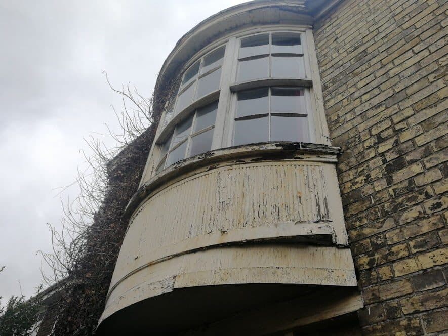 A weathered timber bay window on an old brick building
