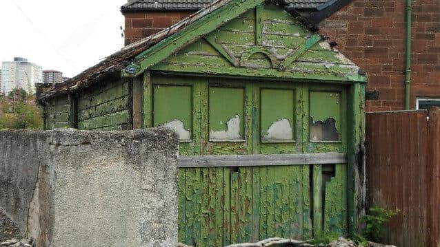 An old timber garage with peeling green paint